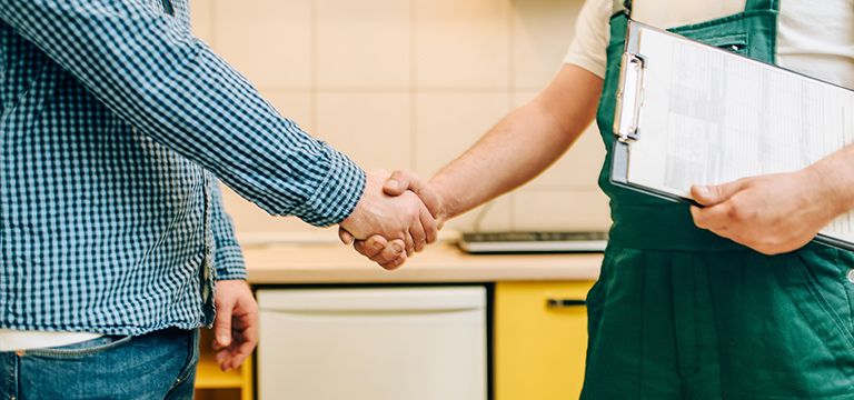 Plumber shaking hands with client.