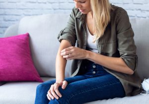 Woman scratching arm from dry skin due to hard water 