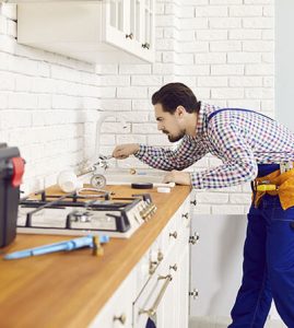 a plumber at a kitchen sink fixing a sign of a plumbing problem