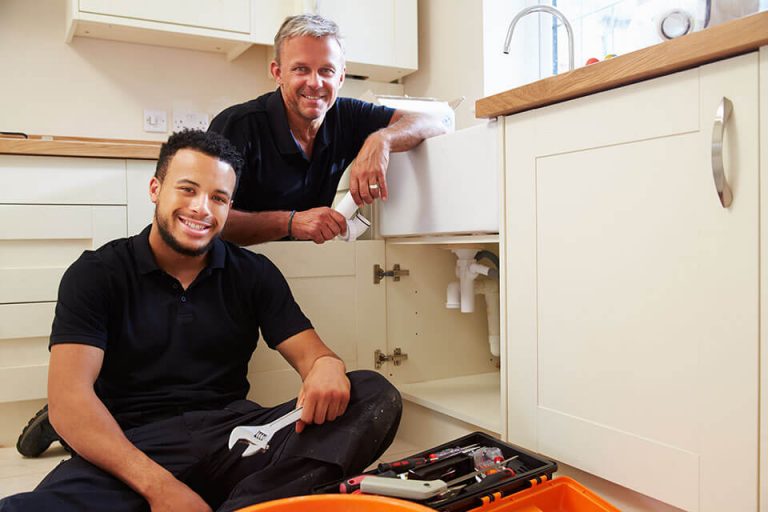 Smiling plumber with his apprentice.