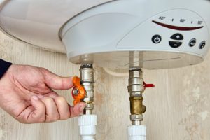 A person adjusting the temperature on their water heater.